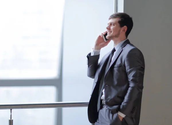 Крупним планом.бізнесмен розмовляє по смартфону, стоячи біля офісного вікна — стокове фото