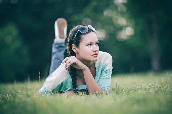 Krásná mladá žena ležící na trávě a dívající se do kamery — Stock fotografie