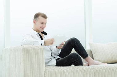 onun oturma odasında kanepede oturan dijital tablet ile gülümseyen adam