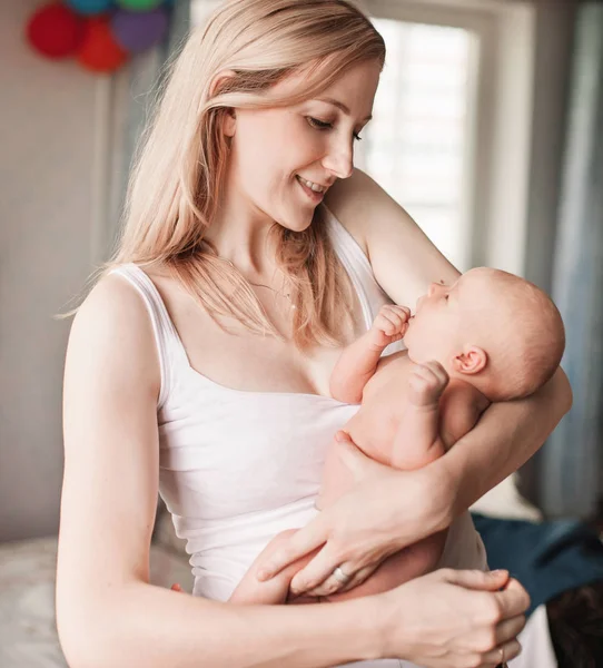 happy mom smiles at her newborn baby .