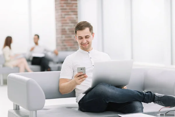 Homem moderno usa gadgets sentados no lobby de um hotel moderno — Fotografia de Stock