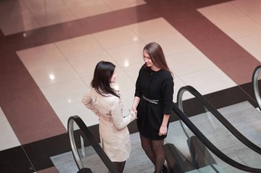 söz, iş merkezinde yürüyen merdiven üzerinde duran iki iş kadınları