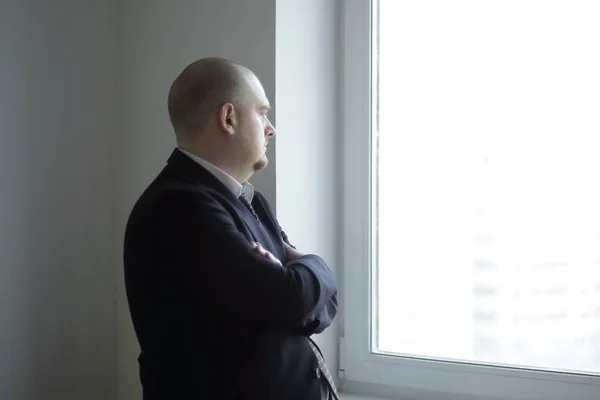 Pensativo hombre de negocios mirando una ventana de oficina en blanco —  Fotos de Stock