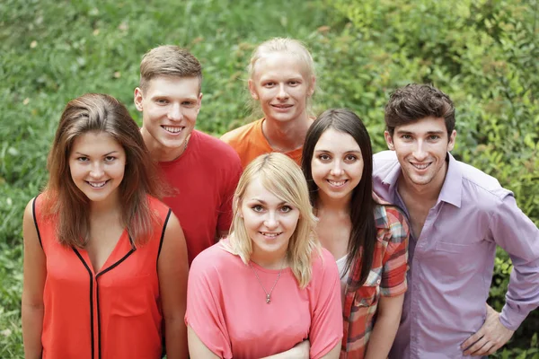 Portret utytułowanej grupy młodych ludzi na zielonym trawniku — Zdjęcie stockowe