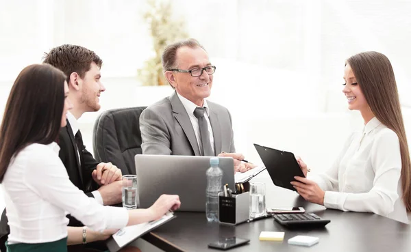 Gerente discutindo problemas de trabalho com seus assistentes atrás de uma mesa — Fotografia de Stock