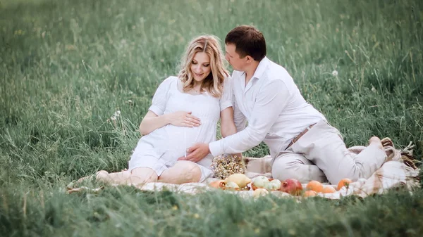 Krásný manželský pár sedí na trávě během pikniku — Stock fotografie