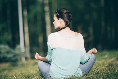 arka görüş. genç kadın Sunny Park konumda Lotus meditasyon