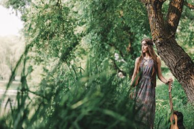 bir orman gölet yakınındaki bir gitar konumu olan güzel hippi kız