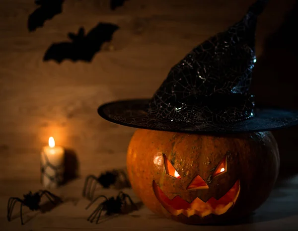 creepy pumpkin for Halloween in witch hat on wooden background