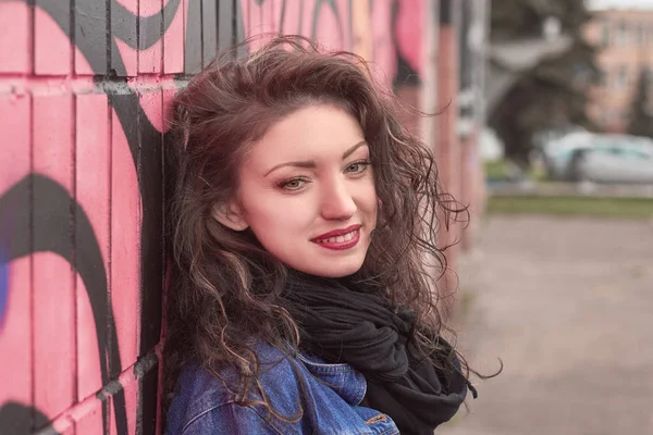 Düşünceli genç bir kadın duvarın önünde duruyor..