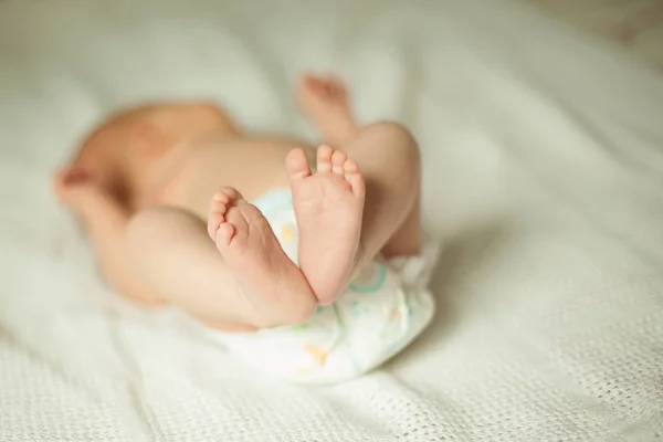 Láb újszülött csecsemő feküdt egy fehér takaró. — Stock Fotó