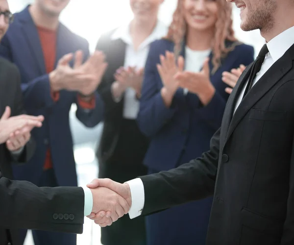 Zblízka. handshake obchodních partnerů na pozadí tleskají obchodní tým — Stock fotografie