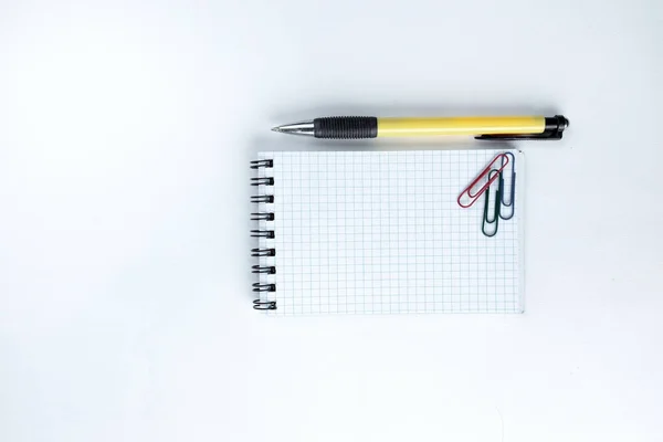 Kladblok, pen en papier clip op witte achtergrond .photo met kopie ruimte — Stockfoto