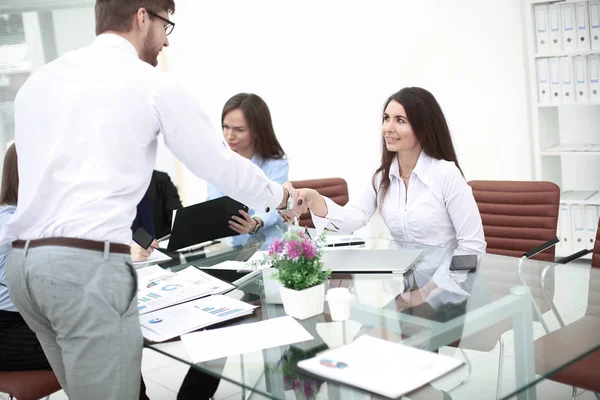 Hombres y mujeres compañeros estrechando las manos sobre la mesa, manteniendo contacto visual — Foto de Stock