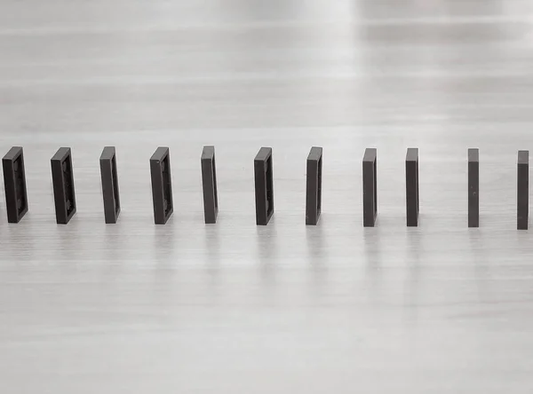 Närbild. Domino marker är byggda i rad på skrivbordet affärsmannen — Stockfoto
