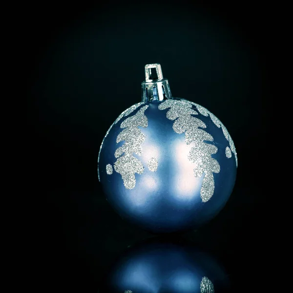 Bola de Natal azul brilhante em um fundo preto . — Fotografia de Stock