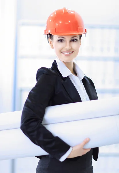 Självsäker kvinnlig ingenjör med ritningar i bakgrunden av kontoret. — Stockfoto