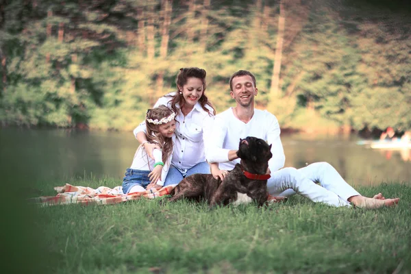 Familia feliz con perro mascota en el picnic en un día soleado de verano. pregn —  Fotos de Stock