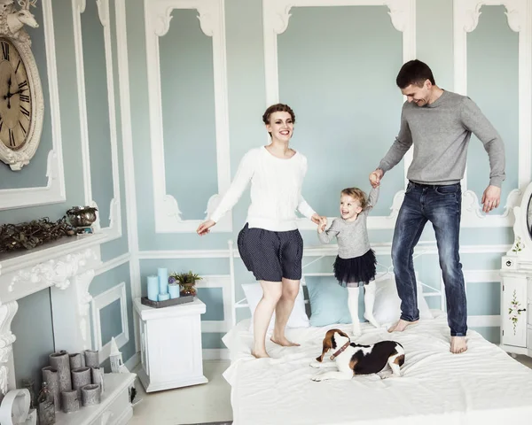 Concepto de felicidad familiar: padres cariñosos jugando con la hija en la cama en el dormitorio — Foto de Stock