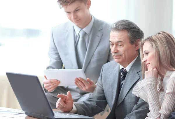 Hombre de negocios señala su mano en la pantalla del ordenador portátil para mostrar información a los colegas — Foto de Stock