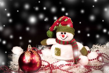 eğlenceli oyuncak kardan adam ve siyah arka planda Noel süslemeleri