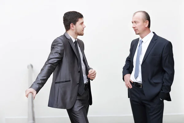 Dos empresarios exitosos discutiendo asuntos de negocios en el vestíbulo de la oficina . — Foto de Stock