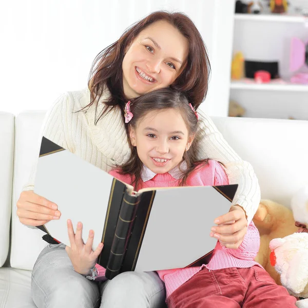 Portret van de moeder en dochter met een boek, zittend op de couch.photo met kopie ruimte — Stockfoto