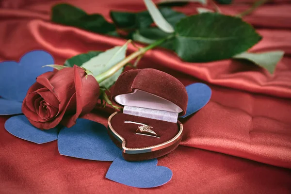 Diamantring und Rose auf leuchtend rotem Hintergrund — Stockfoto