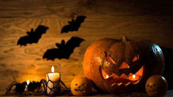 Linda calabaza para Halloween, vela y murciélagos en la mesa de madera —  Fotos de Stock