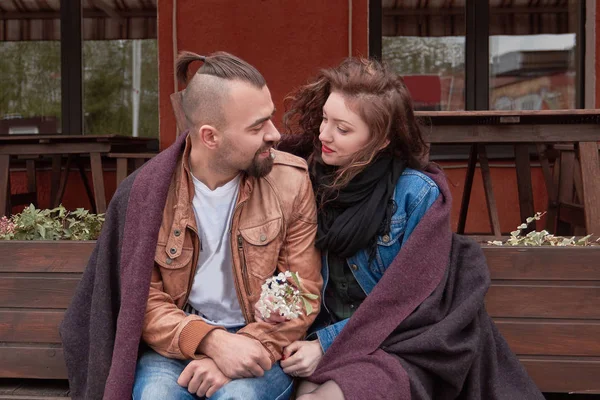 Jovem casal sentado em um banco perto de um café de rua — Fotografia de Stock