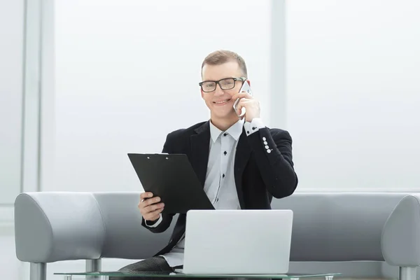 Jeune homme d'affaires parlant sur mobile, assis à son bureau — Photo