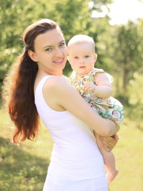 Anne ve mutlu kızı parkta bir yürüyüş üzerinde gülümseyen