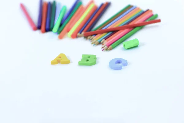 Lápices de colores y letras del alfabeto sobre un fondo blanco .photo con espacio para copiar —  Fotos de Stock