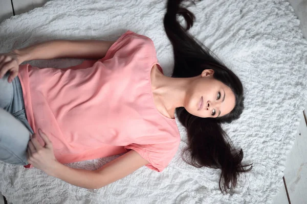 Övre view.young kvinna liggande på vit matta i vardagsrummet — Stockfoto