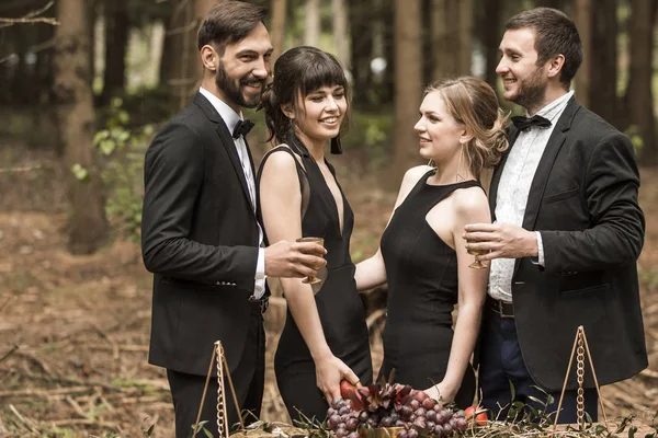 Due giovani coppie amorevoli in abiti da lavoro che fanno un picnic nel parco . — Foto Stock