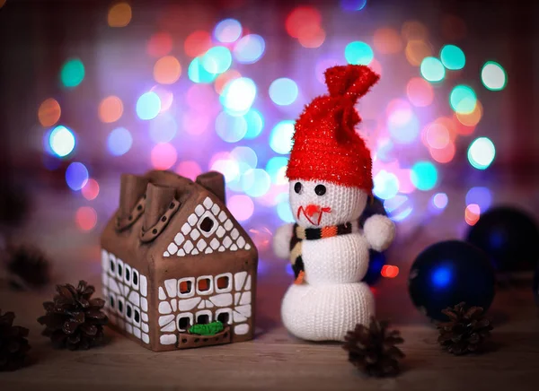 Spielzeugschneemann und Lebkuchenhaus am Weihnachtstisch — Stockfoto
