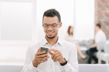 Genç adam onun Smartphone'da SMS okuma gülümseyerek