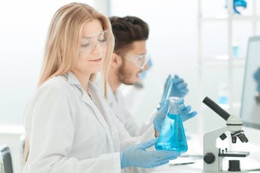 Yakın çekim. Genç bilim adamları sıvı üzerinde deney yapıyorlar.