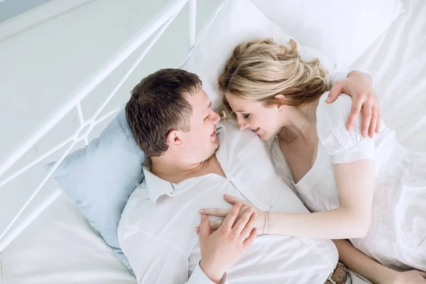 Suami yang peduli dan istrinya yang sedang hamil berbaring di tempat tidur . — Stok Foto
