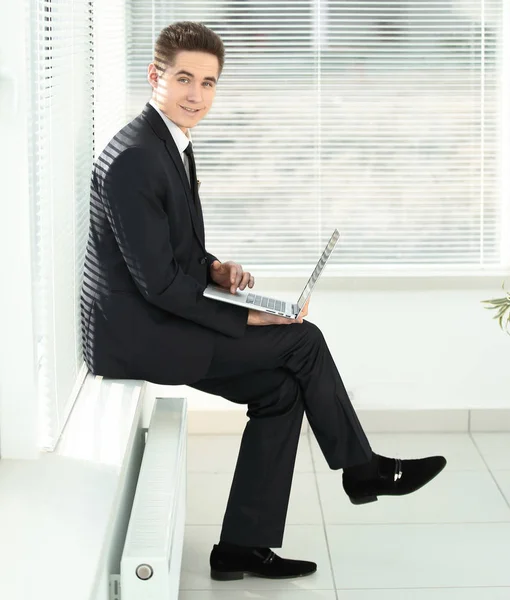 Young employee working on a laptop sitting in the corridor of the office — Stock Photo, Image