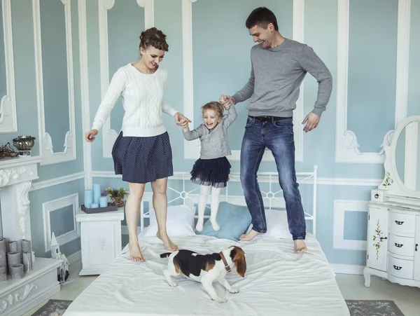 Concepto de felicidad familiar: padres cariñosos jugando con la hija en la cama en el dormitorio — Foto de Stock