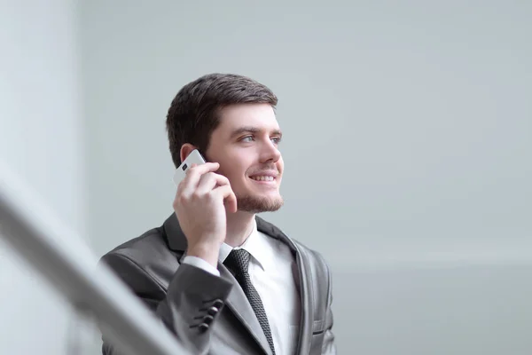 Close up. smiling businessman talking on smartphone in office — стоковое фото