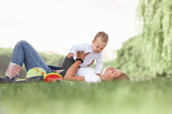 Mom and her little son play together, lying on the lawn . — Stock Photo, Image