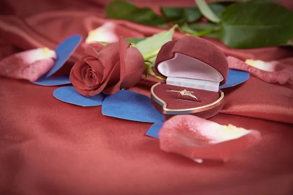 Diamantring und Rose auf leuchtend rotem Hintergrund — Stockfoto