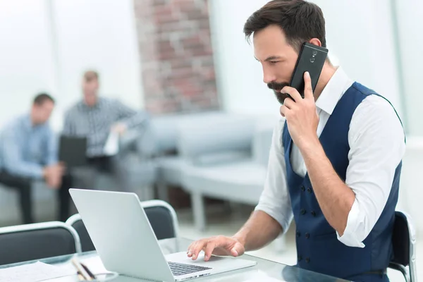 Business man talking on a smartphone sitting at his Desk — стоковое фото