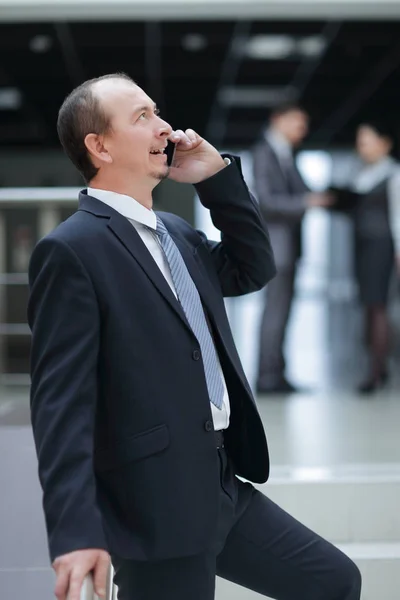 Hombre de negocios sonriente hablando por teléfono móvil en la oficina — Foto de Stock