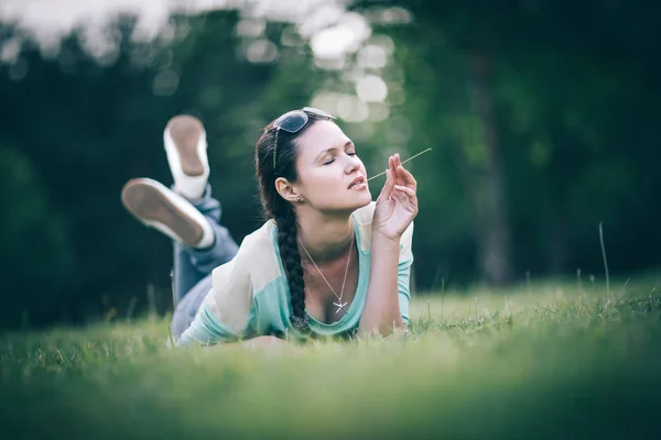 Pensive young woman lying on the grass on a good day — Stock Photo, Image