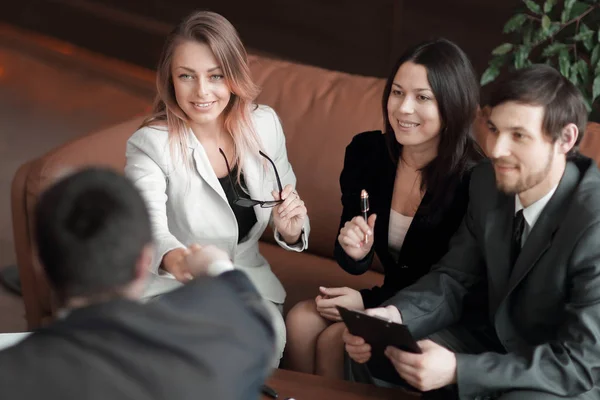 Stäng up.business kvinnan skakar hand med affärspartner som sitter på jobbet skrivbord — Stockfoto