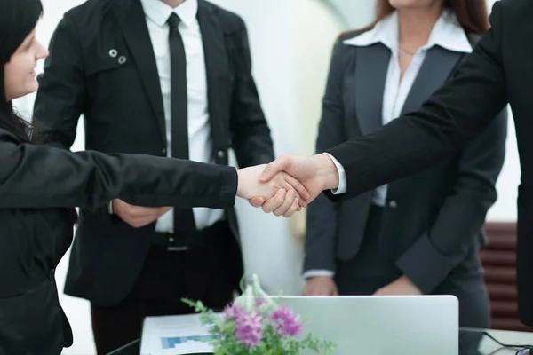 Dos empresarias dando la mano sobre un escritorio mientras cierran un trato — Foto de Stock