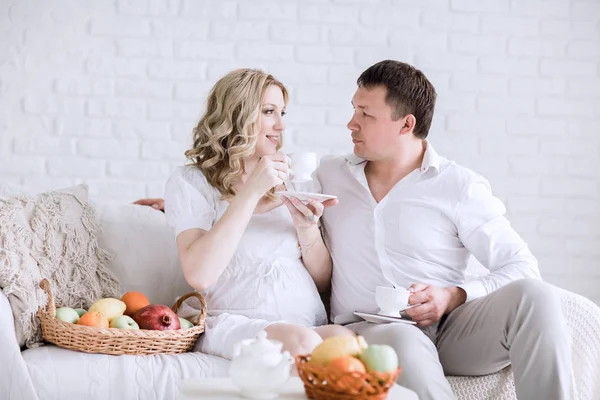 Man en zijn zwangere vrouw hebben ontbijt zittend op de Bank — Stockfoto